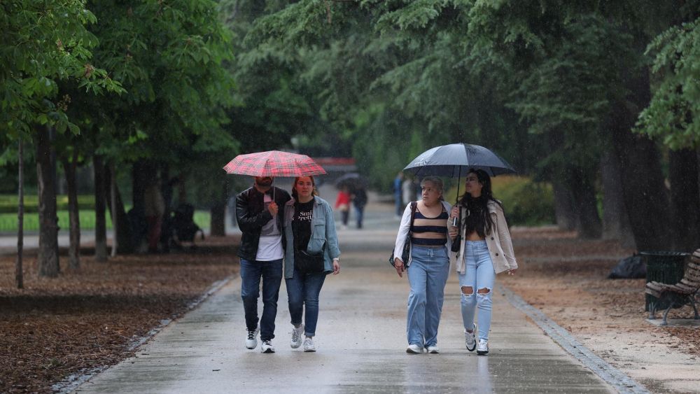 Varias personas atraviesan un parque bajo la lluvia en València