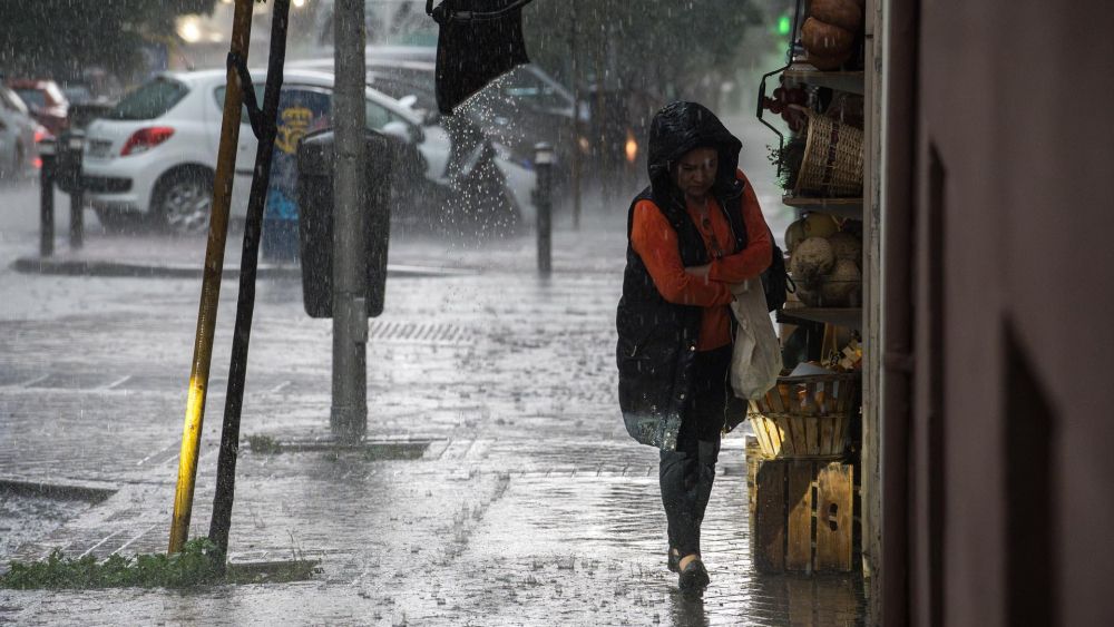 Una mujer se resguarda en Valencia de un episodio de lluvia torrencial durante una tormenta. Imagen de Diego Radamés