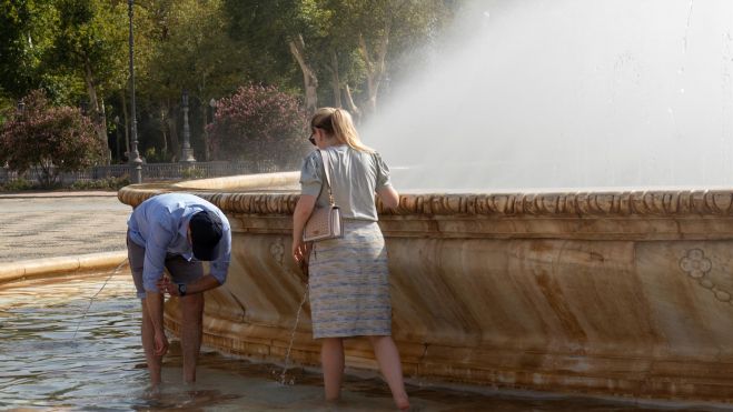 Dos personas se refrescan en una fuente de València por el calor