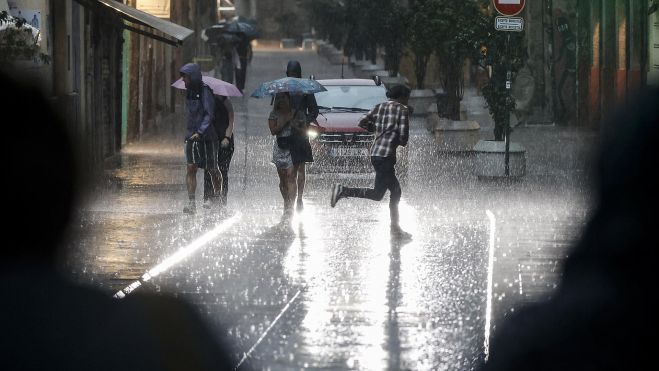 Gente andando por la calle en València bajo la lluvia