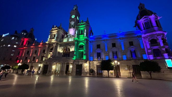 La fachada del edificio del Ayuntamiento de València iluminada con los colores de la bandera arcoíris