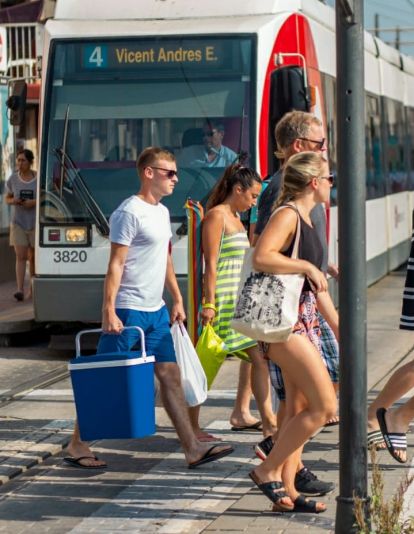 Un grup de persones arriba a la platja de València en un tramvia de Metrovalencia