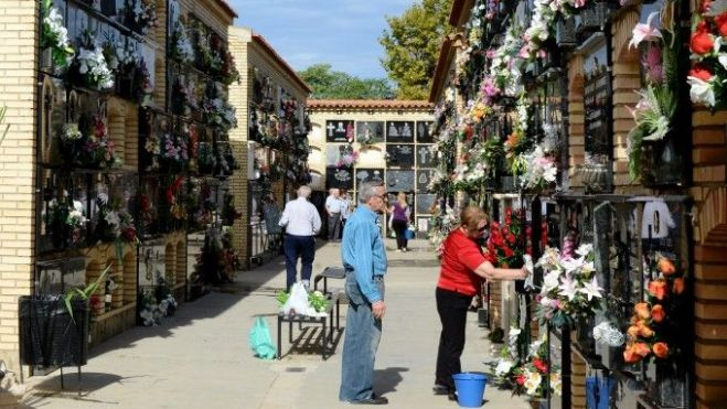 Gent posant flors al cementeri en Tots Sants